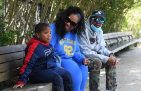 Selena Martinez sits on a park bench with her son Blake and her husband in Brooklyn, NY.