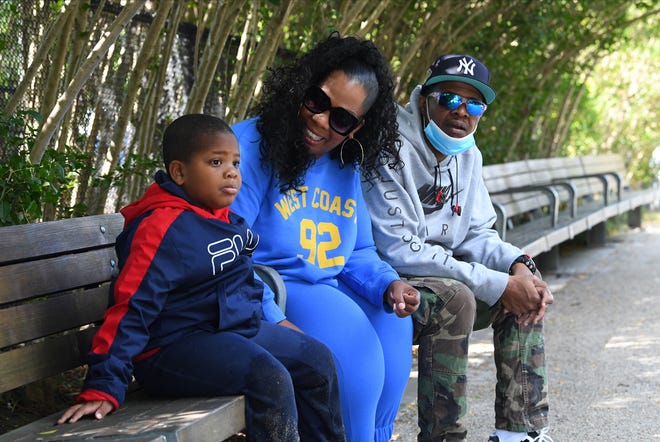 Selena Martinez sits on a park bench with her son Blake and her husband in Brooklyn, NY.