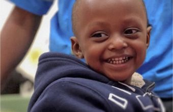 A little boy wearing a navy blue jacket while smiling.