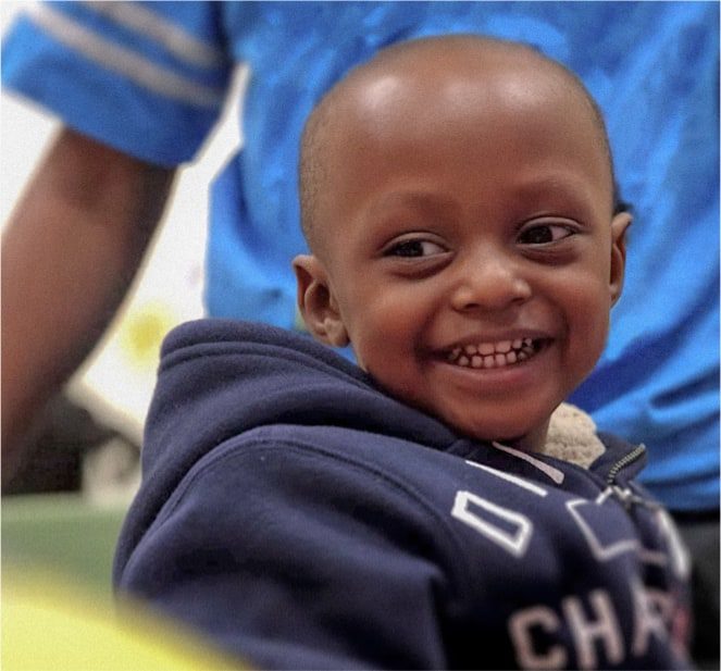 A little boy wearing a navy blue jacket while smiling.