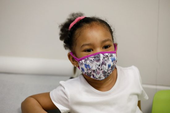 A closeup of a little girl wearing a face mask.