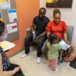 Parents and child in pediatrician's office meet with health care provider.